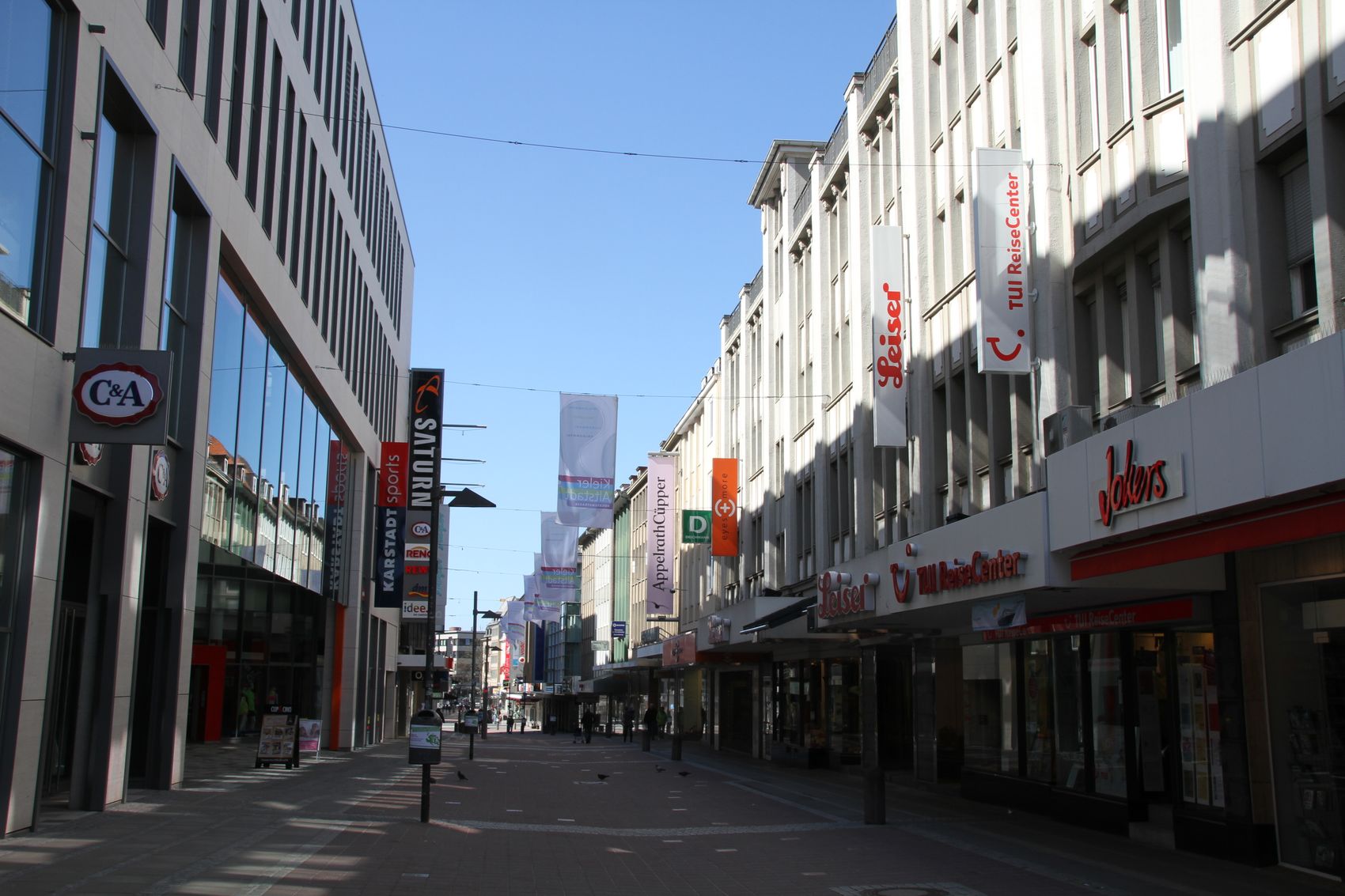 Fußgängerzone Holstenstraße in Kiel mit mehrstöckigen Kaufhausfassaden und Schaufenstern bei Tageslicht